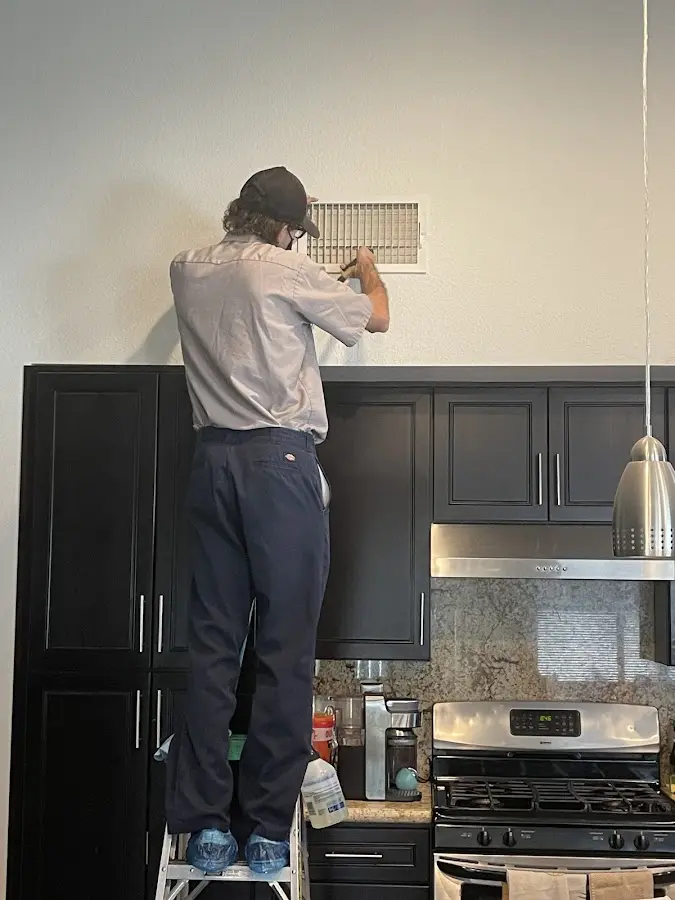 Technician inspecting an air vent during HVAC service in Country Club Estates
